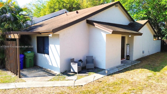 view of home's exterior featuring roof with shingles and stucco siding