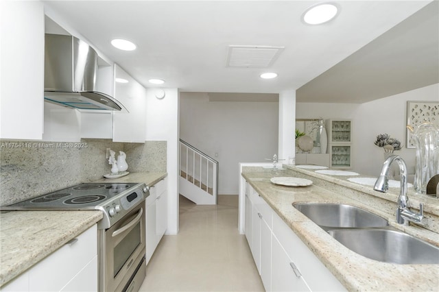 kitchen with electric range, a sink, visible vents, white cabinets, and wall chimney range hood