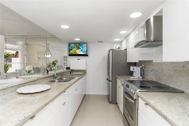 kitchen featuring white cabinets, decorative backsplash, wall chimney exhaust hood, stainless steel appliances, and a sink