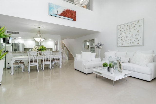 living area featuring visible vents, a high ceiling, and stairs