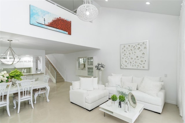 living room with a towering ceiling, stairs, a chandelier, and recessed lighting