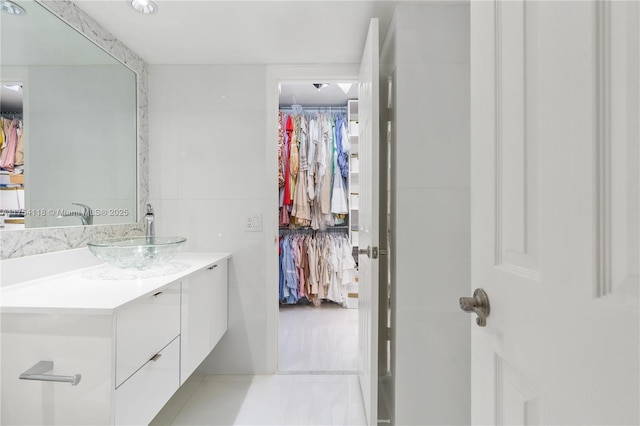 bathroom with a walk in closet and vanity