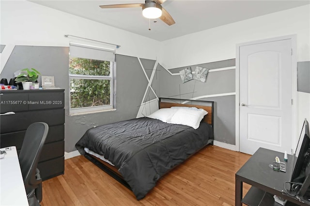 bedroom with a ceiling fan, wood finished floors, and baseboards