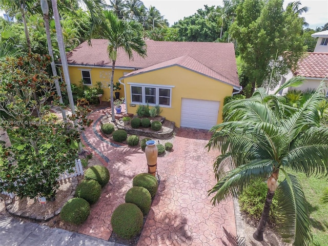 view of front facade featuring stucco siding, decorative driveway, roof with shingles, and an attached garage