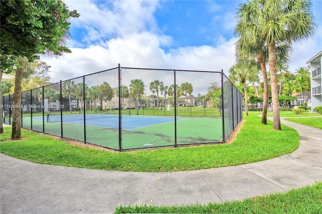 view of tennis court featuring fence and a lawn