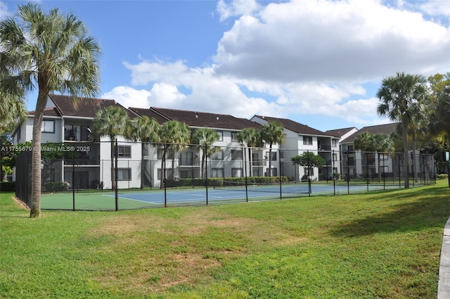 view of tennis court featuring a residential view, fence, and a yard