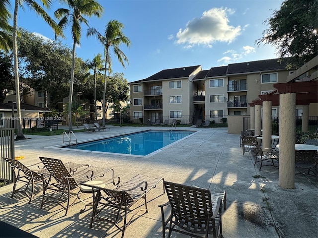 community pool featuring a residential view, a patio area, and fence