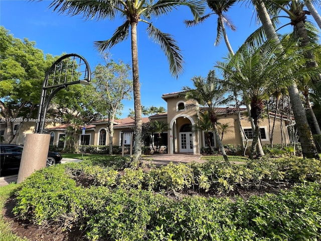 exterior space with french doors, a tile roof, and stucco siding