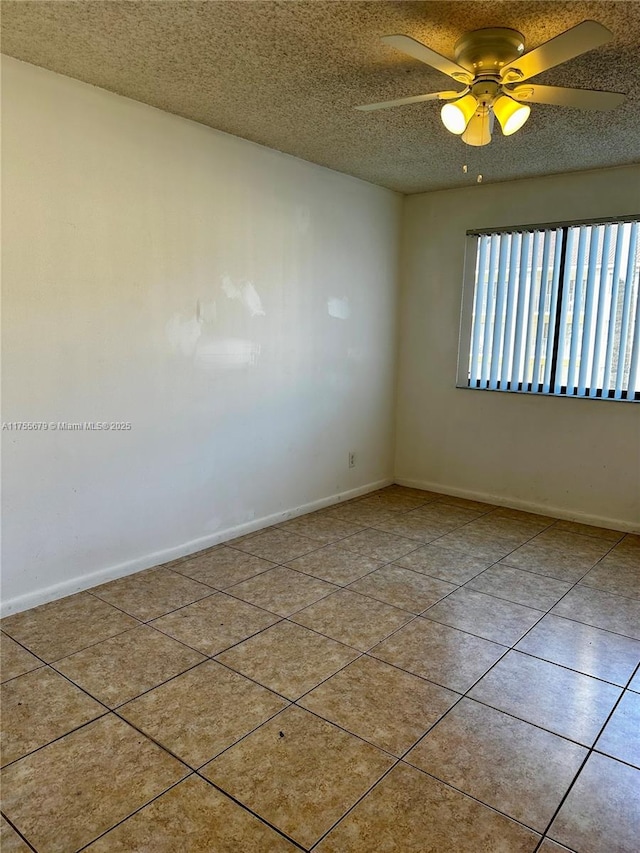 spare room with a textured ceiling, tile patterned flooring, a ceiling fan, and baseboards