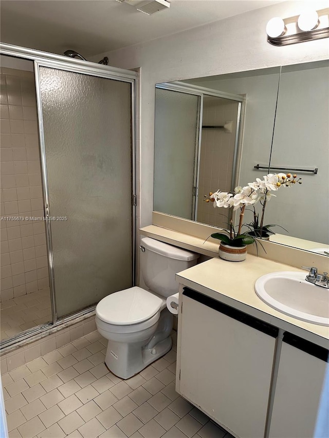 bathroom with toilet, a shower stall, vanity, and tile patterned floors