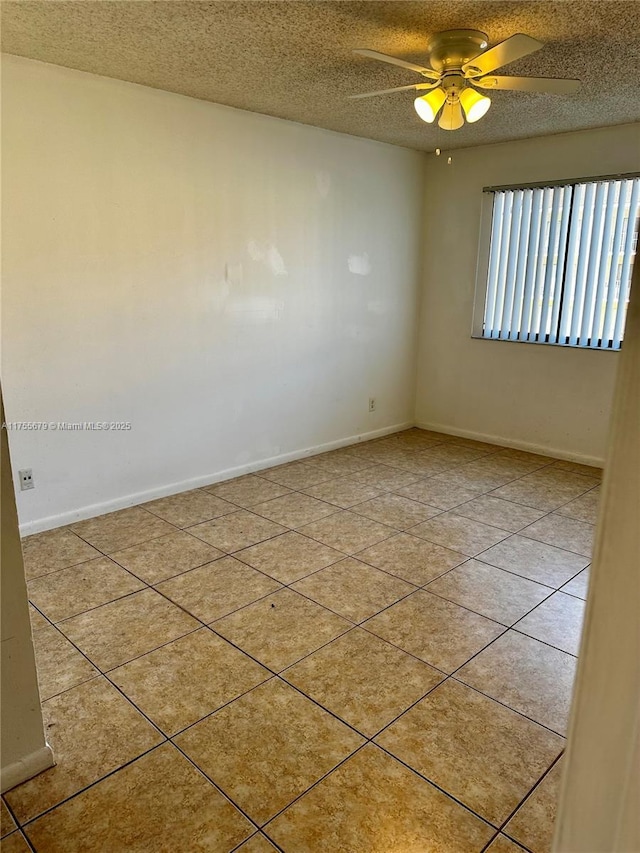 tiled spare room with a textured ceiling, ceiling fan, and baseboards