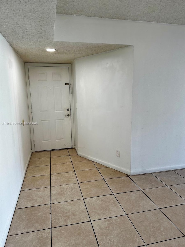 unfurnished room featuring baseboards, a textured ceiling, and light tile patterned flooring