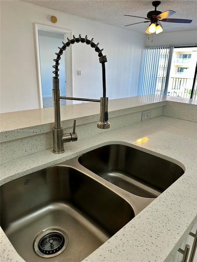 interior details with light stone countertops, a textured ceiling, and a sink