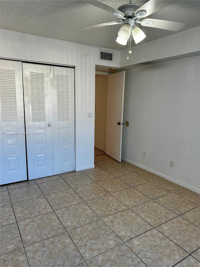 unfurnished bedroom with a closet, visible vents, a textured ceiling, and light tile patterned flooring