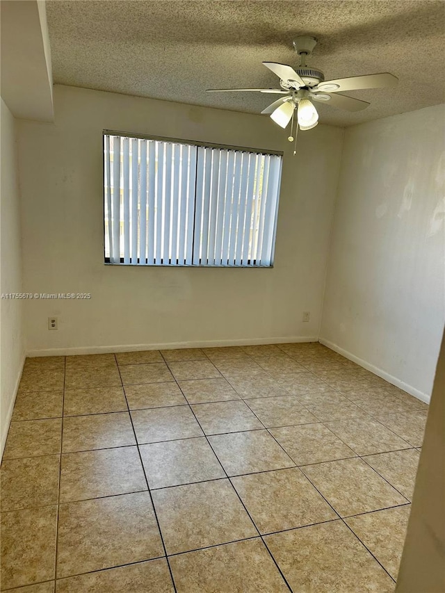 tiled spare room featuring ceiling fan, baseboards, and a textured ceiling