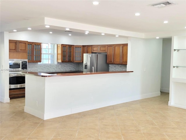 225 191st Ter, Sunny Isles Beach, FL 33160 - kitchen with appliances with stainless steel finishes, recessed lighting, decorative backsplash, brown cabinetry, and glass insert cabinets