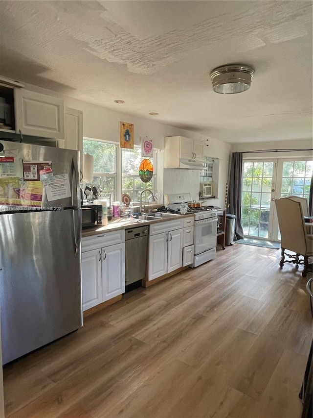 3611 SW 36th St, West Park, FL 33023 - kitchen featuring stainless steel appliances, white cabinetry, light wood-type flooring, and under cabinet range hood