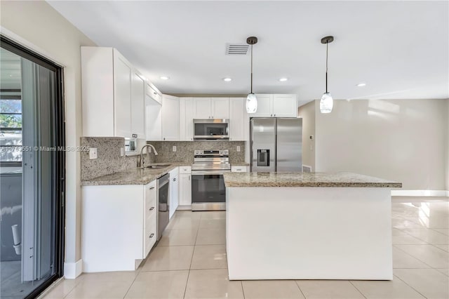 kitchen with tasteful backsplash, a kitchen island, appliances with stainless steel finishes, and light stone counters