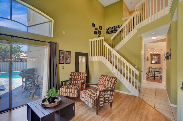 living room featuring baseboards, a towering ceiling, stairway, wood finished floors, and an inviting chandelier