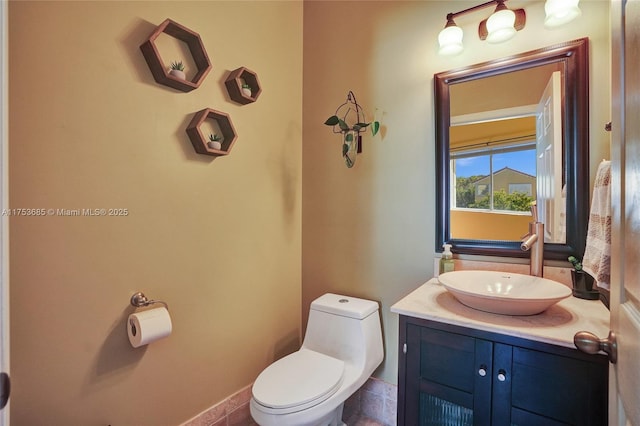 half bath featuring baseboards, vanity, and toilet