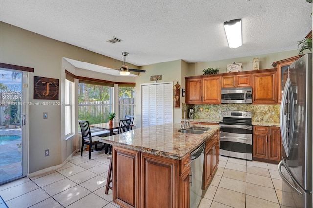 kitchen featuring visible vents, brown cabinetry, decorative backsplash, stainless steel appliances, and a sink