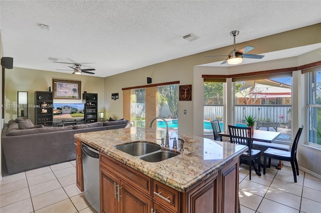 kitchen with a center island with sink, light tile patterned floors, visible vents, a sink, and dishwasher