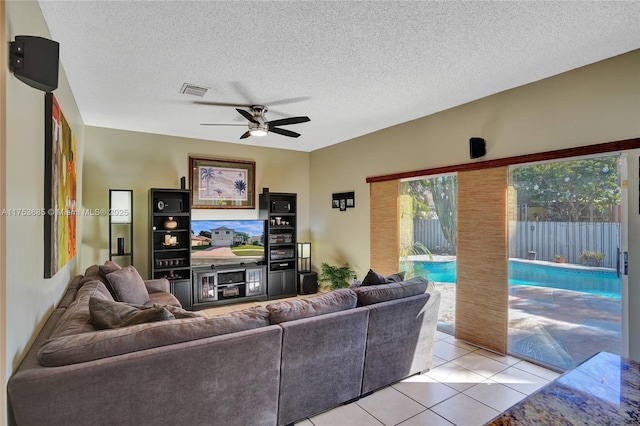 living room featuring visible vents, light tile patterned flooring, ceiling fan, and a textured ceiling