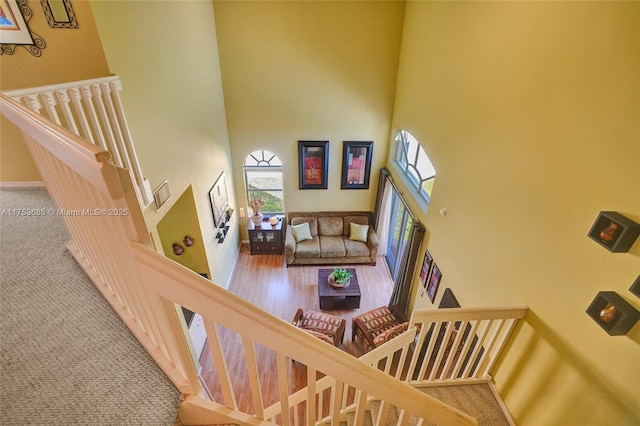 stairway with carpet flooring, a towering ceiling, and baseboards