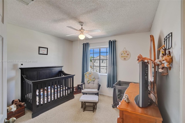 carpeted bedroom with baseboards, visible vents, a ceiling fan, and a textured ceiling