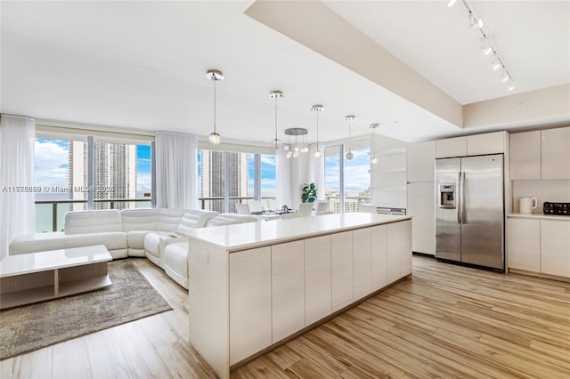 kitchen with light wood-style floors, light countertops, stainless steel refrigerator with ice dispenser, and modern cabinets