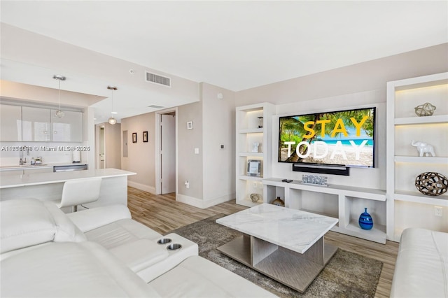 living room featuring visible vents, light wood-style flooring, and baseboards