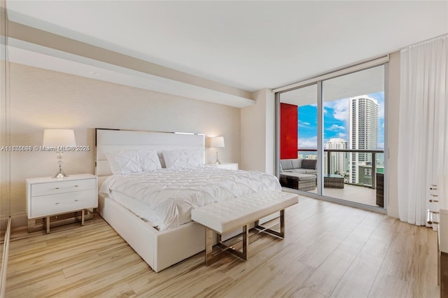 bedroom with a wall of windows, access to outside, and wood finished floors