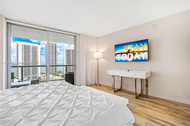 bedroom featuring expansive windows, baseboards, and wood finished floors