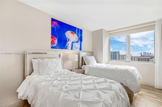 bedroom featuring a view of city, baseboards, and wood finished floors