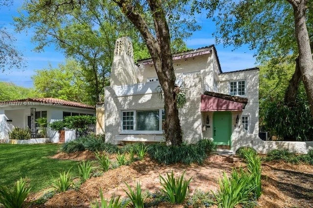 mediterranean / spanish house featuring a front yard, a chimney, and stucco siding