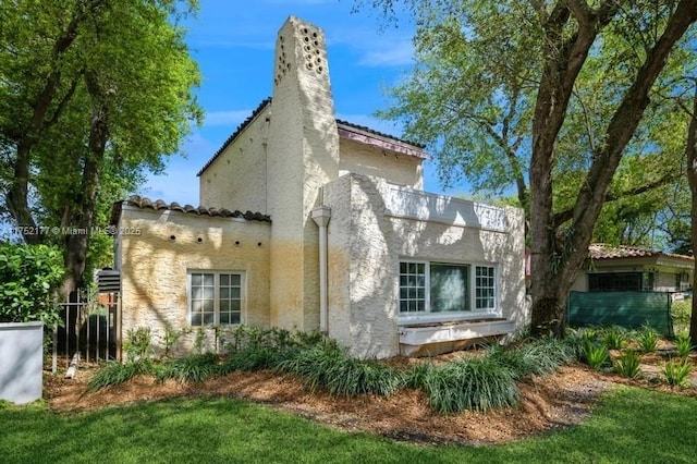 view of side of property featuring a chimney and stucco siding