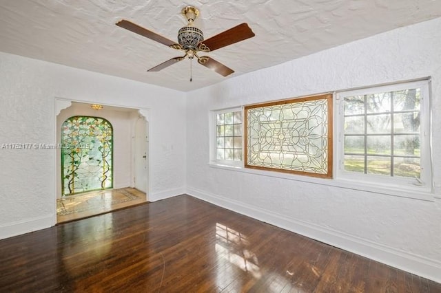 empty room with a ceiling fan, baseboards, a textured wall, and hardwood / wood-style floors