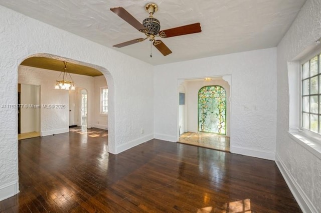 empty room featuring wood-type flooring, arched walkways, and a textured wall