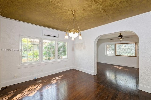 empty room with arched walkways, hardwood / wood-style floors, ornamental molding, an AC wall unit, and baseboards