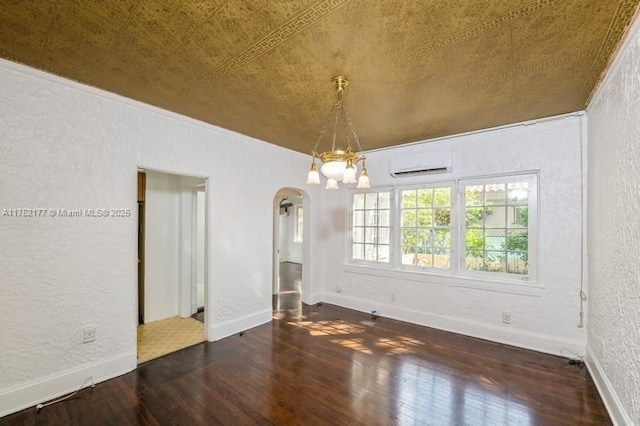 unfurnished room with baseboards, arched walkways, a textured wall, hardwood / wood-style floors, and a chandelier