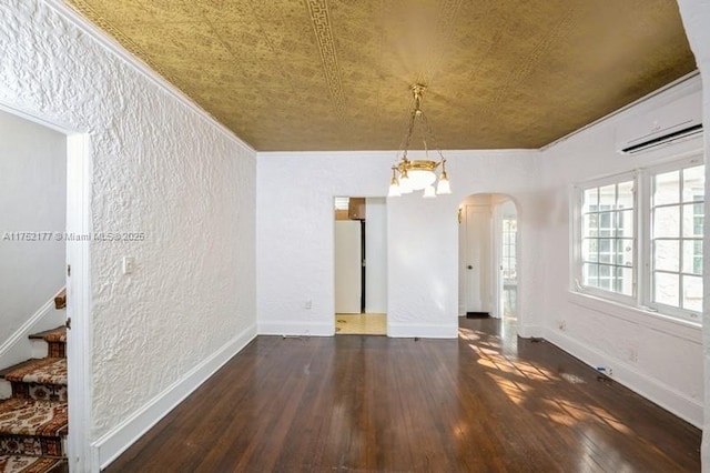 unfurnished dining area with arched walkways, baseboards, a textured wall, wood-type flooring, and a wall mounted AC