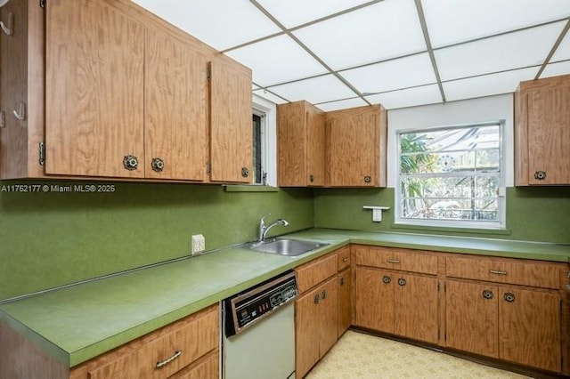 kitchen featuring white dishwasher, light countertops, a paneled ceiling, light floors, and a sink