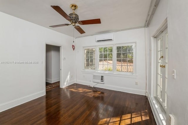 spare room with an AC wall unit, wood finished floors, and baseboards