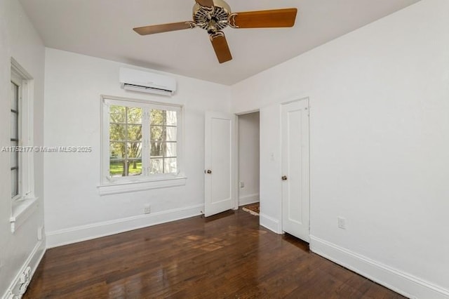 unfurnished bedroom with a ceiling fan, an AC wall unit, baseboards, and wood finished floors