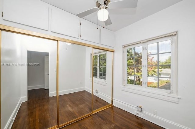 unfurnished bedroom with ceiling fan, dark wood-style flooring, a closet, and baseboards