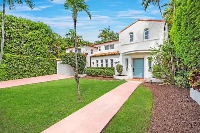 mediterranean / spanish-style home with a tiled roof, a front lawn, and stucco siding