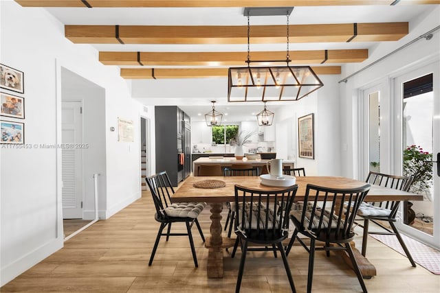 dining room featuring beamed ceiling, light wood-style flooring, and baseboards