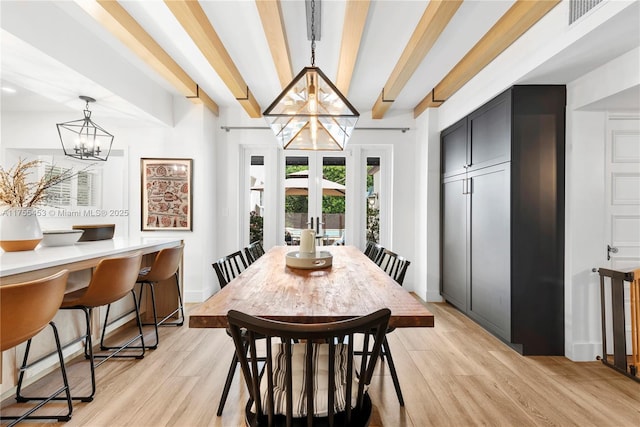 dining space featuring light wood-type flooring, beam ceiling, a notable chandelier, and french doors