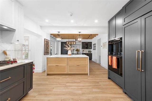 kitchen featuring light wood-type flooring, dobule oven black, tasteful backsplash, and light countertops