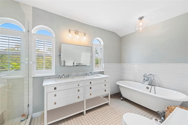 full bathroom featuring double vanity, a soaking tub, a sink, and tile walls